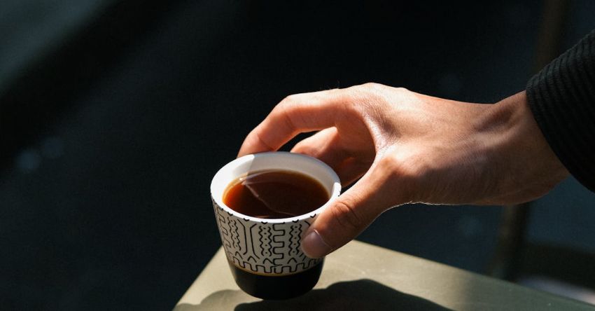 Hand-Lettering - A person holding a cup of coffee on a table